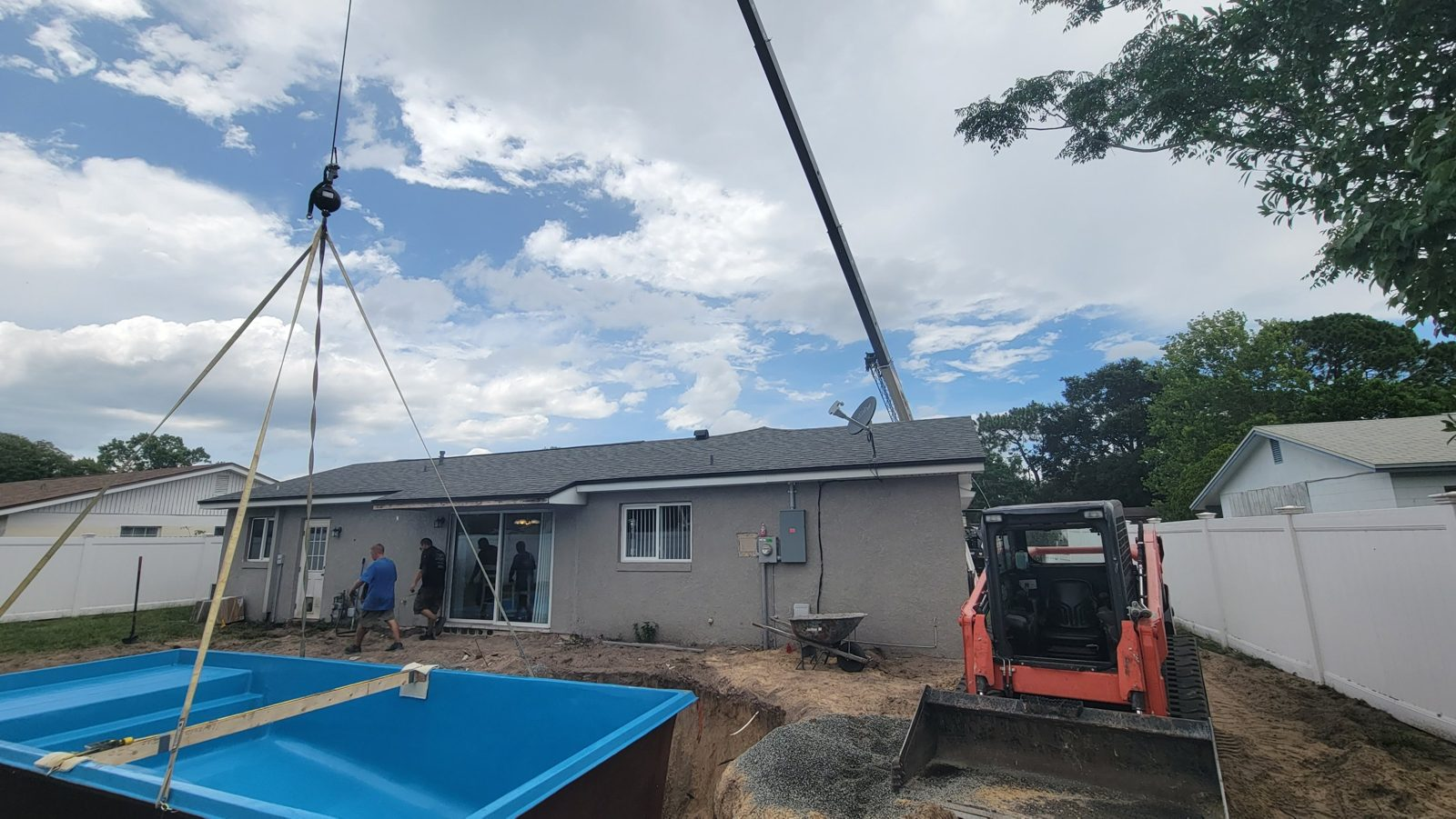 Crane lifting a fiberglass pool shell over a house in Casselberry, Florida
