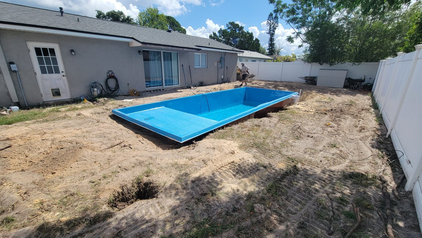 Fiberglass pool shell set in a backyard beside a house