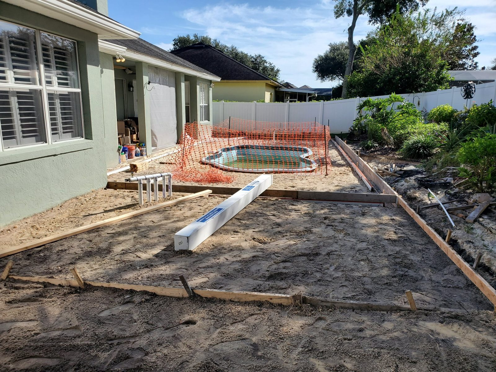 Wood deck forms around a fiberglass pool beside a house