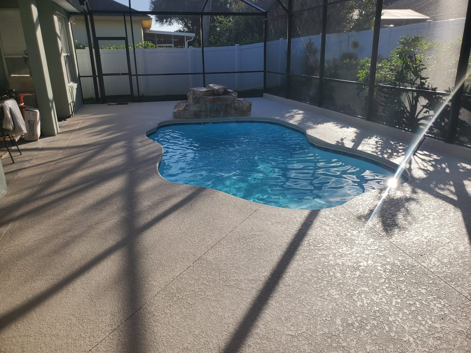 Fiberglass pool with an acrylic knockdown deck inside a screen enclosure