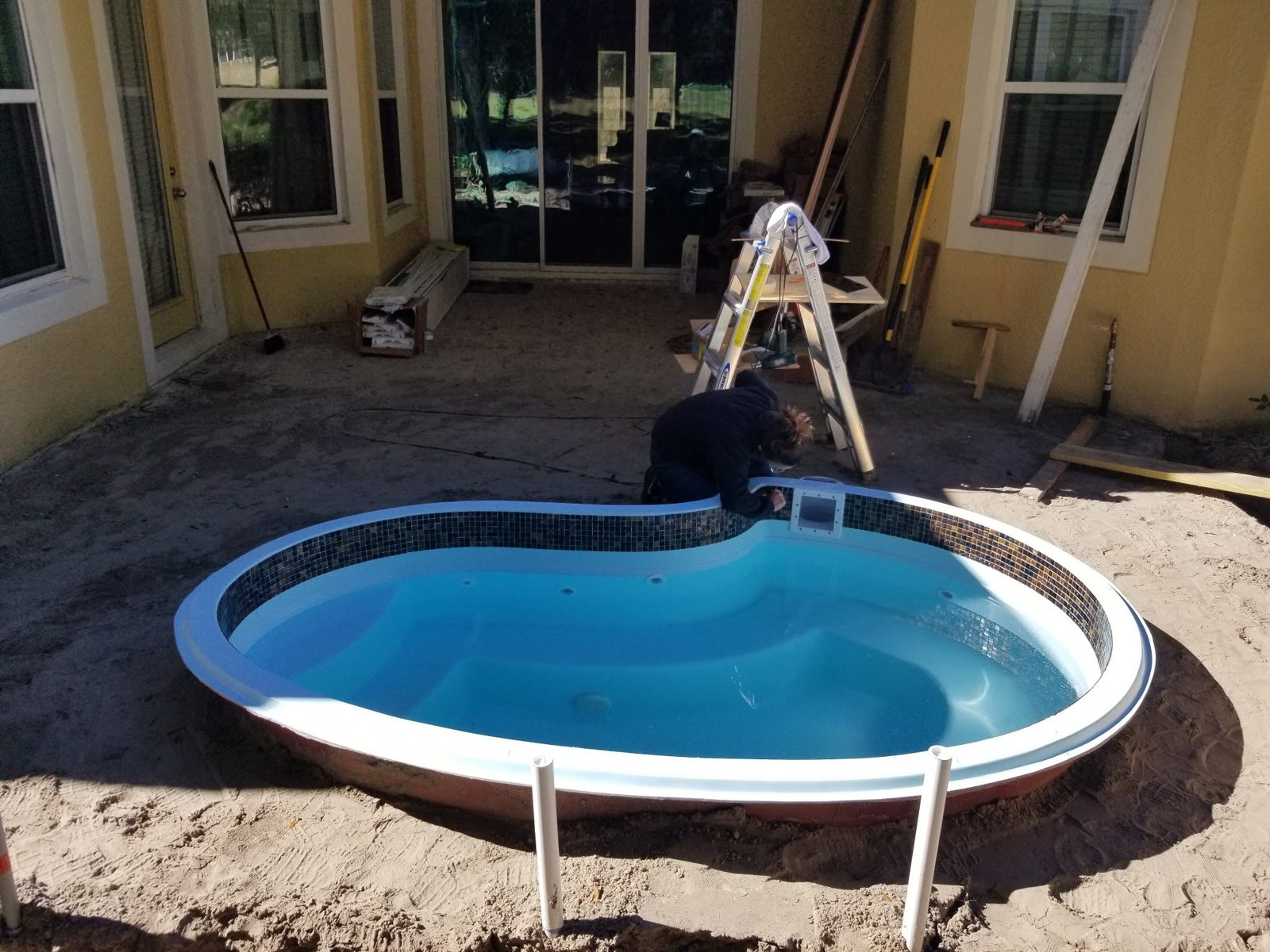 Installer setting glass mosaic waterline tile on a fiberglass spa