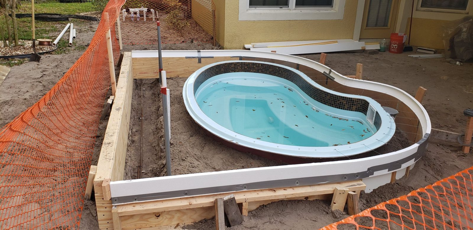 Concrete forms with rebar beside a fiberglass spa
