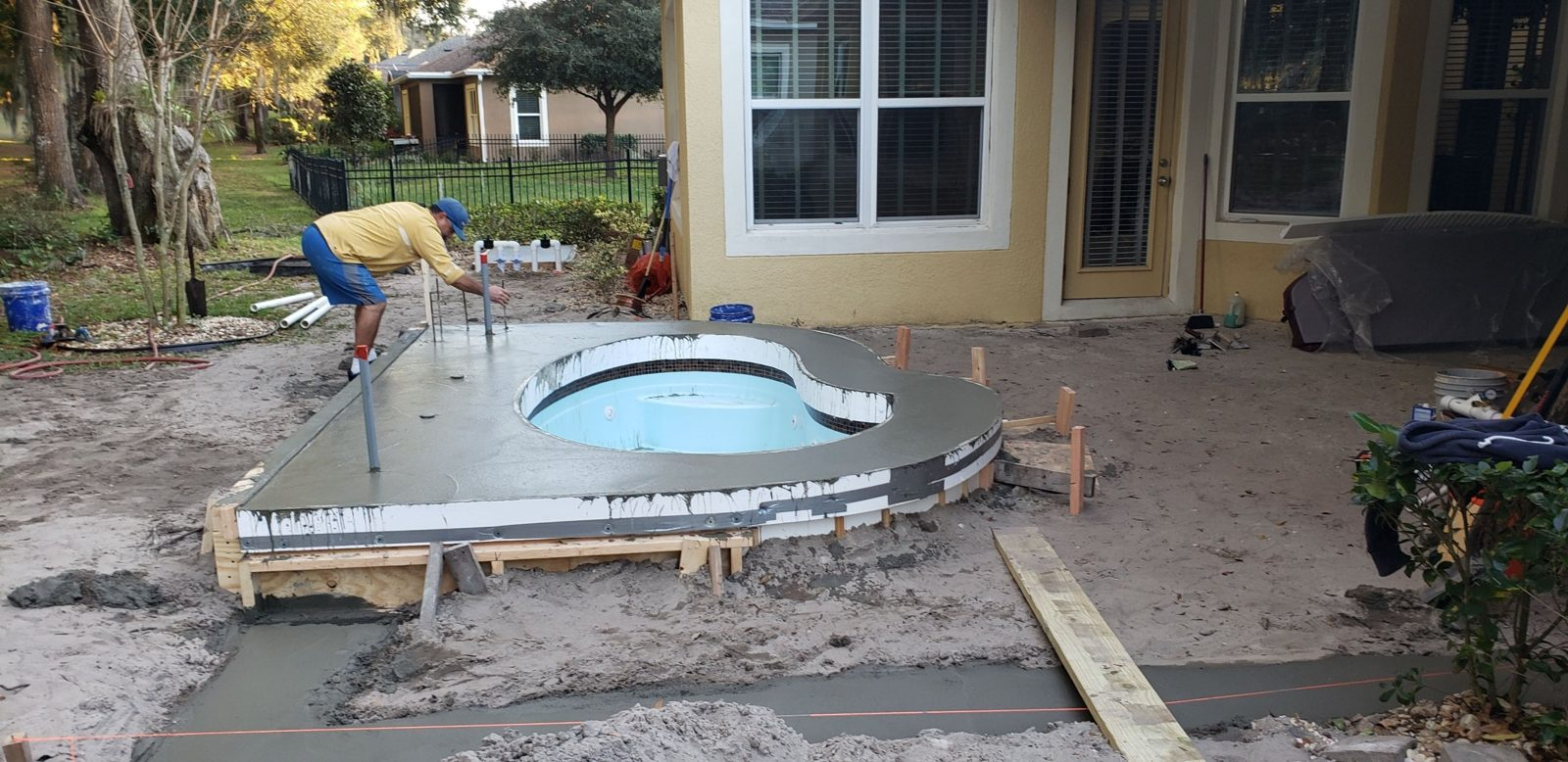 Worker finishing poured concrete around a raised spa