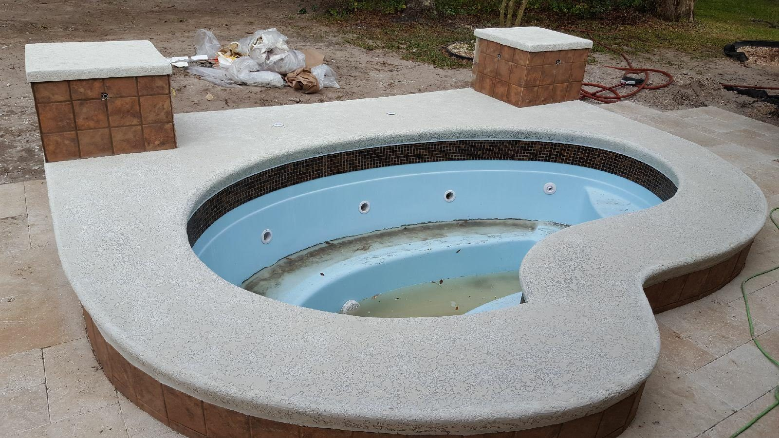 Finished textured coping around an empty fiberglass spa