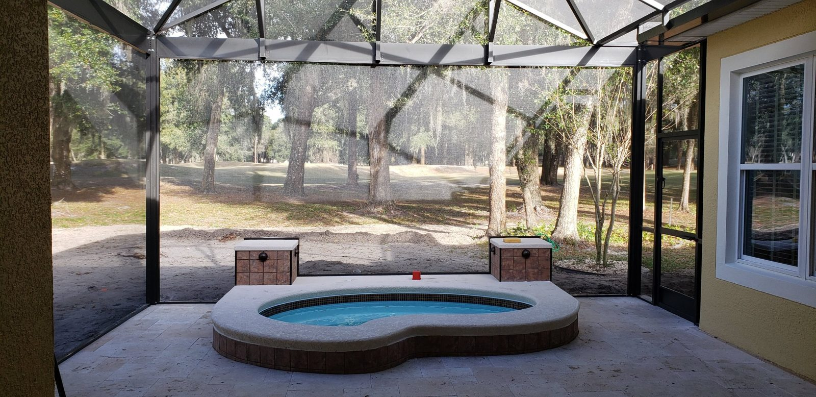 Raised fiberglass spa in a screen enclosure overlooking a golf course