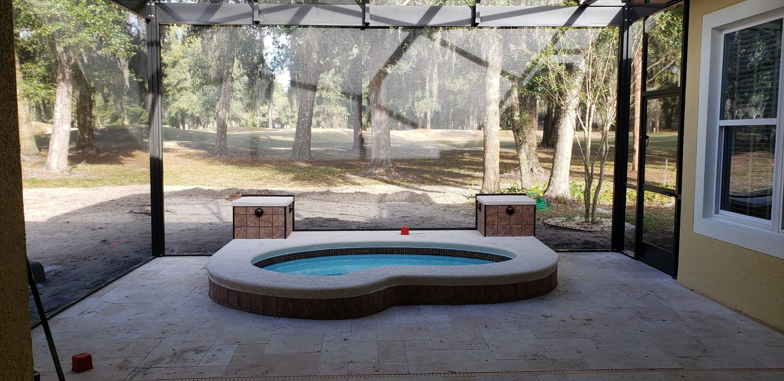 Raised spa with tiled pillars on a travertine patio