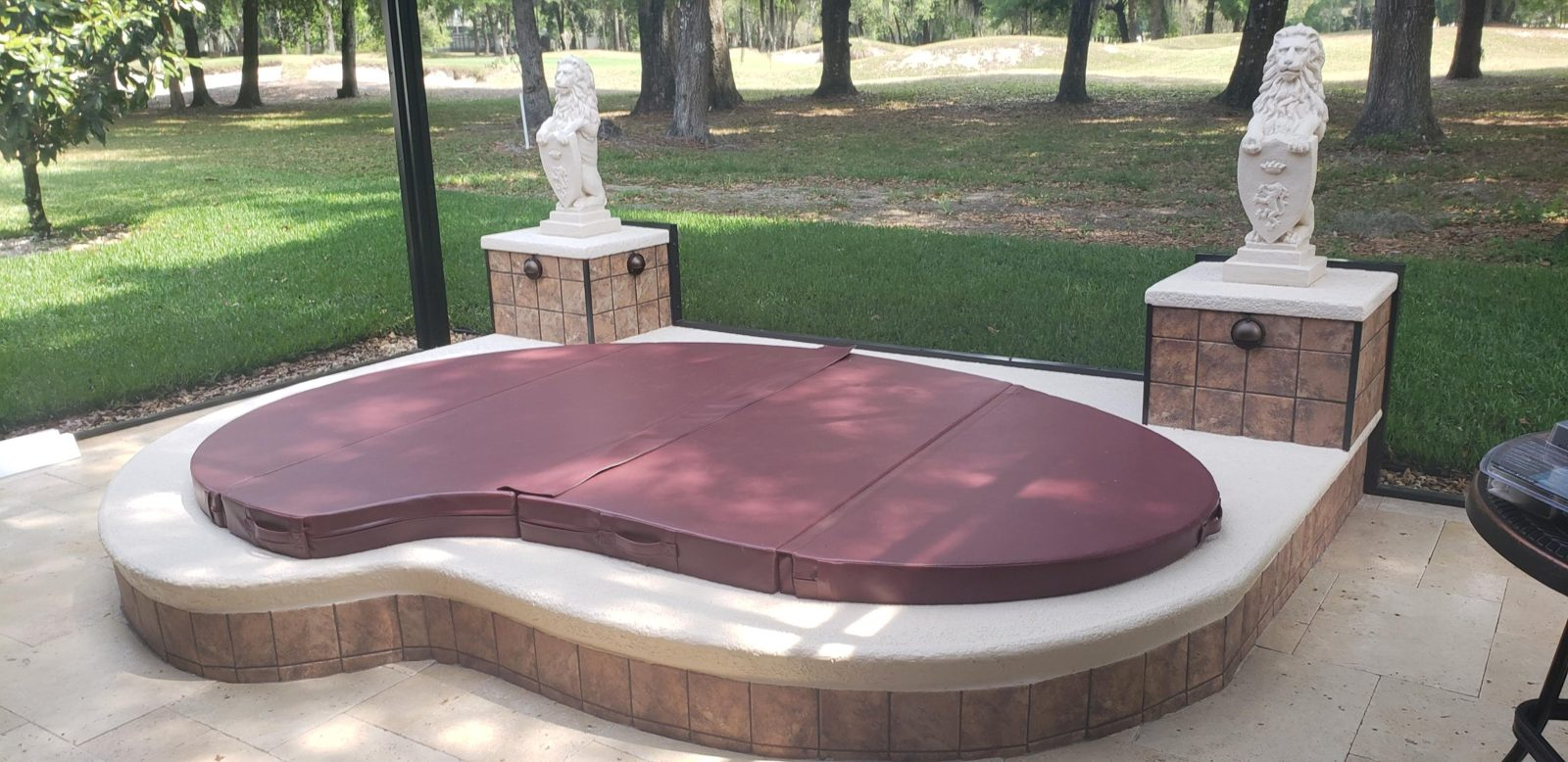 Raised spa with a burgundy cover and stone lion statues