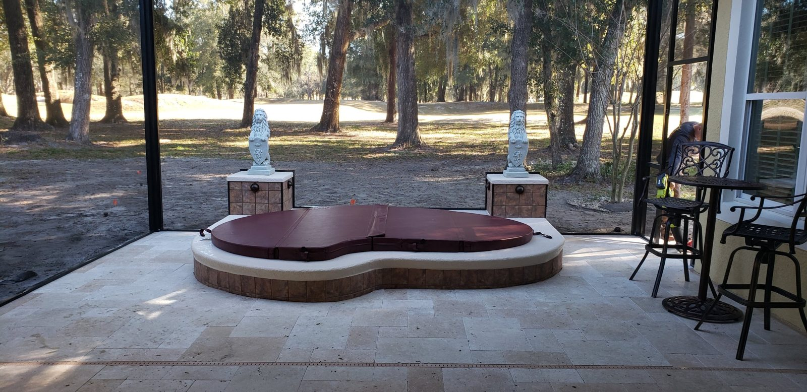 Covered raised spa on a travertine patio with bistro furniture