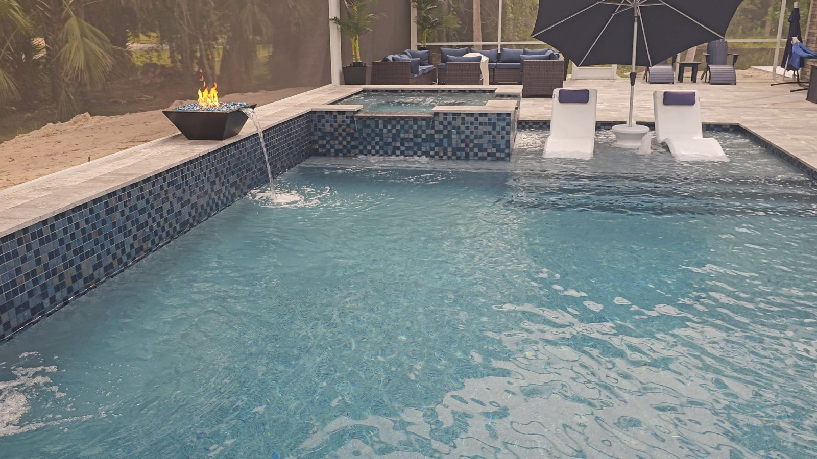 Fire and water bowl spilling into a gunite pool with glass tile