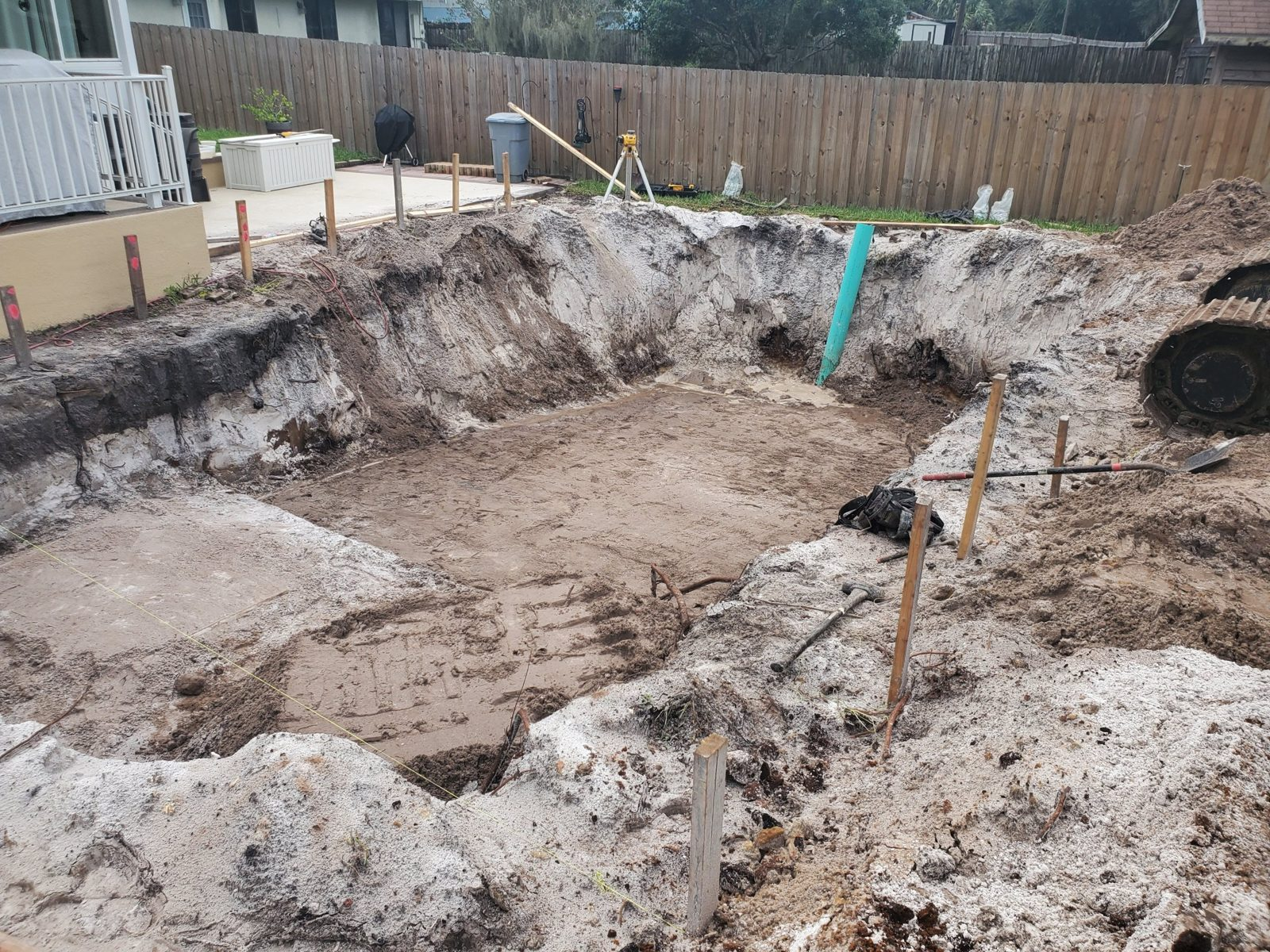 Fiberglass pool excavation in a Deltona backyard with a laser level
