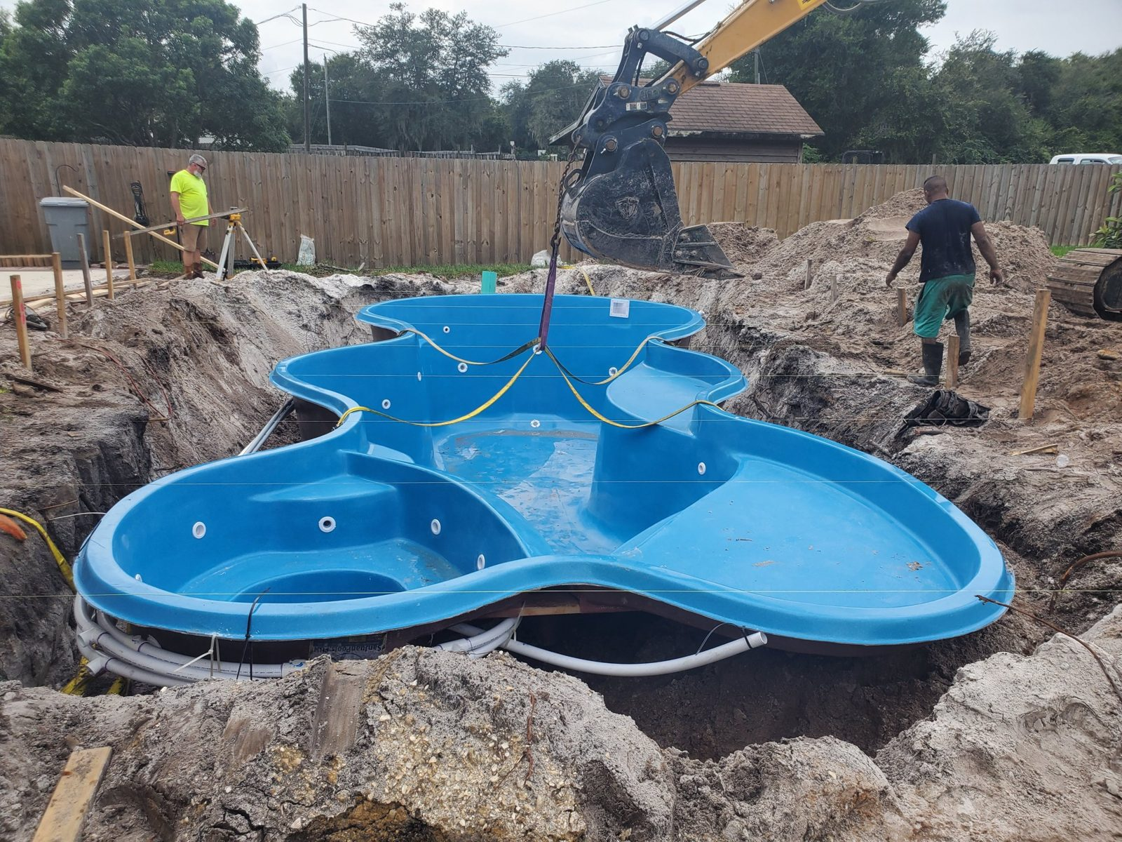 Excavator lowering a San Juan Desert Springs fiberglass pool shell