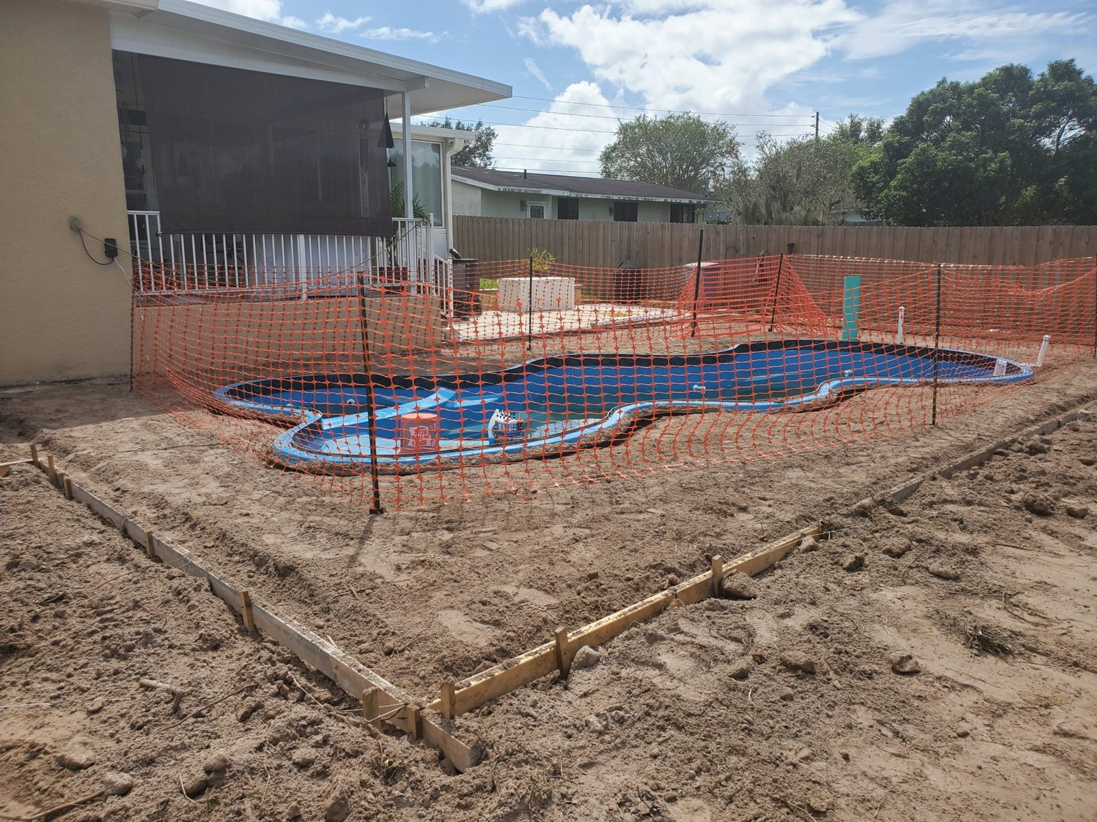 Wood deck forms around a fiberglass pool next to an elevated porch