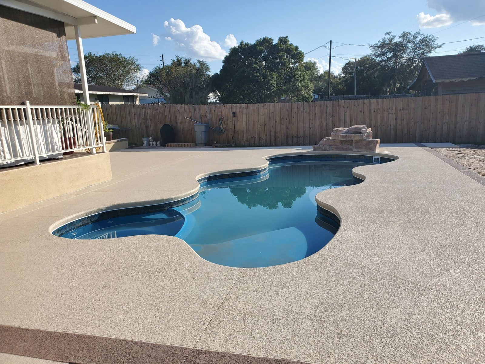 Fiberglass pool with an acrylic knockdown concrete deck and rock waterfall