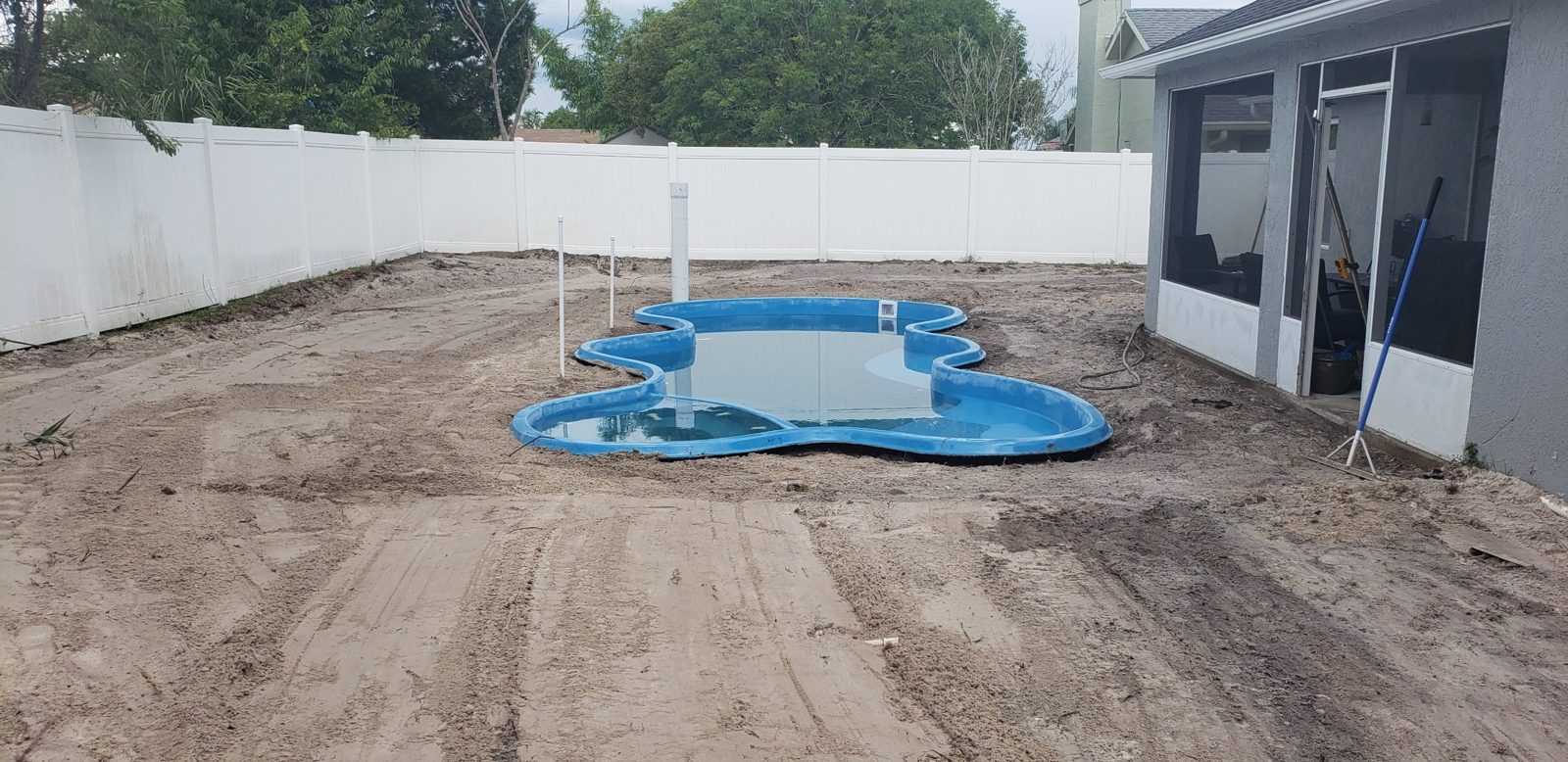 Fiberglass pool shell set level with plumbing stubbed up in a Deltona backyard