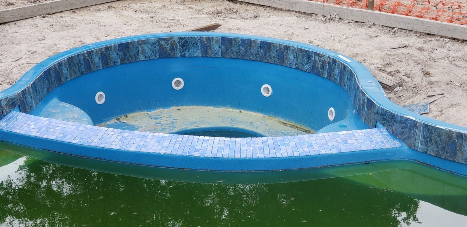Glass mosaic tile on the spa dam of a fiberglass pool and spa