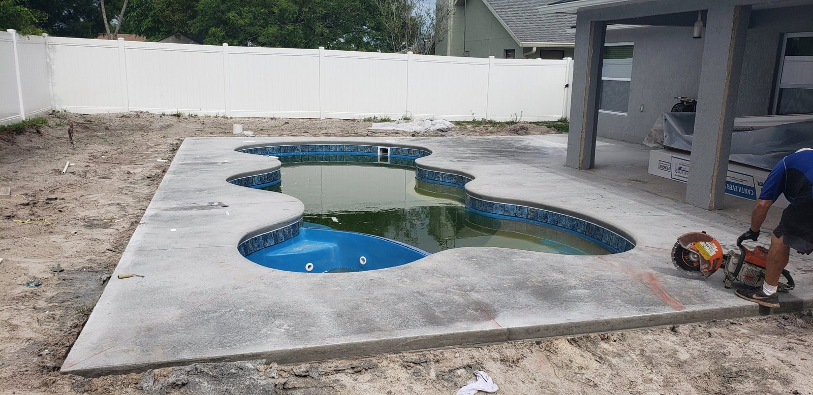 Crew saw-cutting control joints in a new concrete pool deck