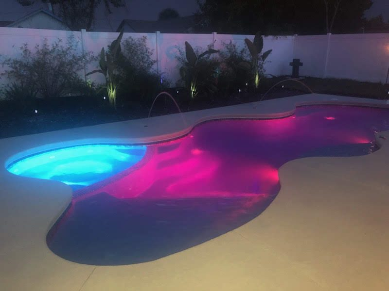 Fiberglass pool lit with color LED lights at night